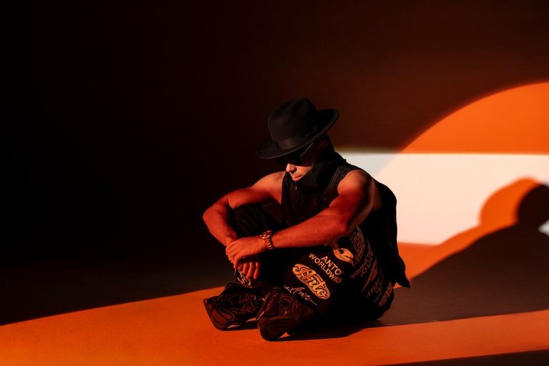 Australian DJ Timmy Trumpet sitting in a black hat under warm spotlighting.